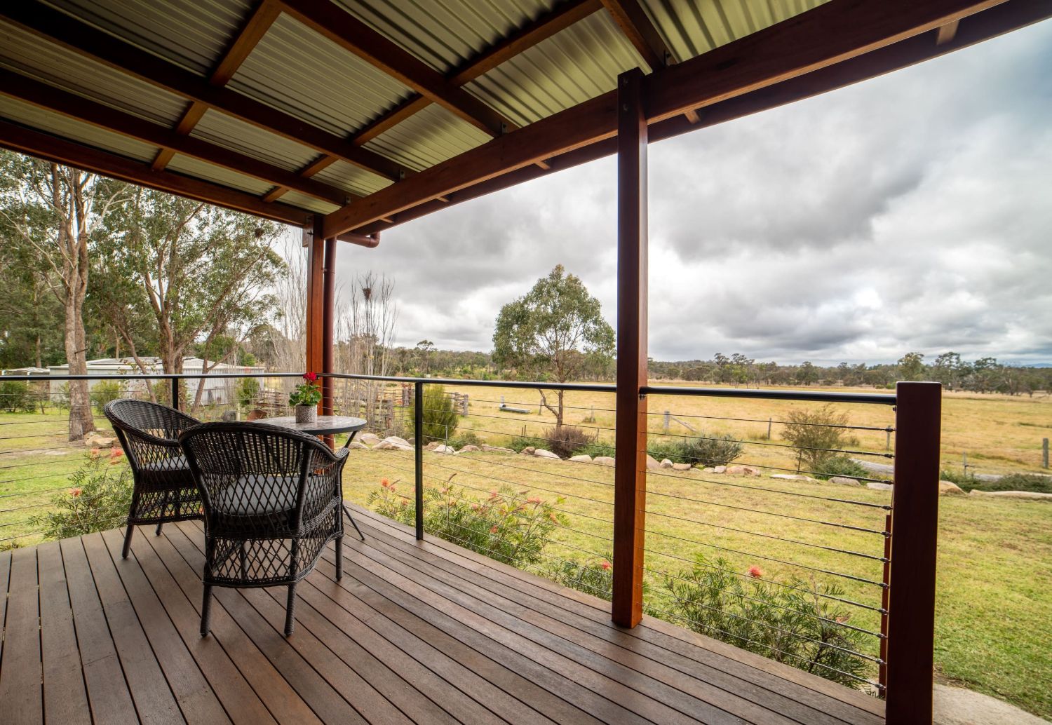 The Yarrabee cottage &mdash; timber and corrugated iron with a covered verandah, ringed by grevillea